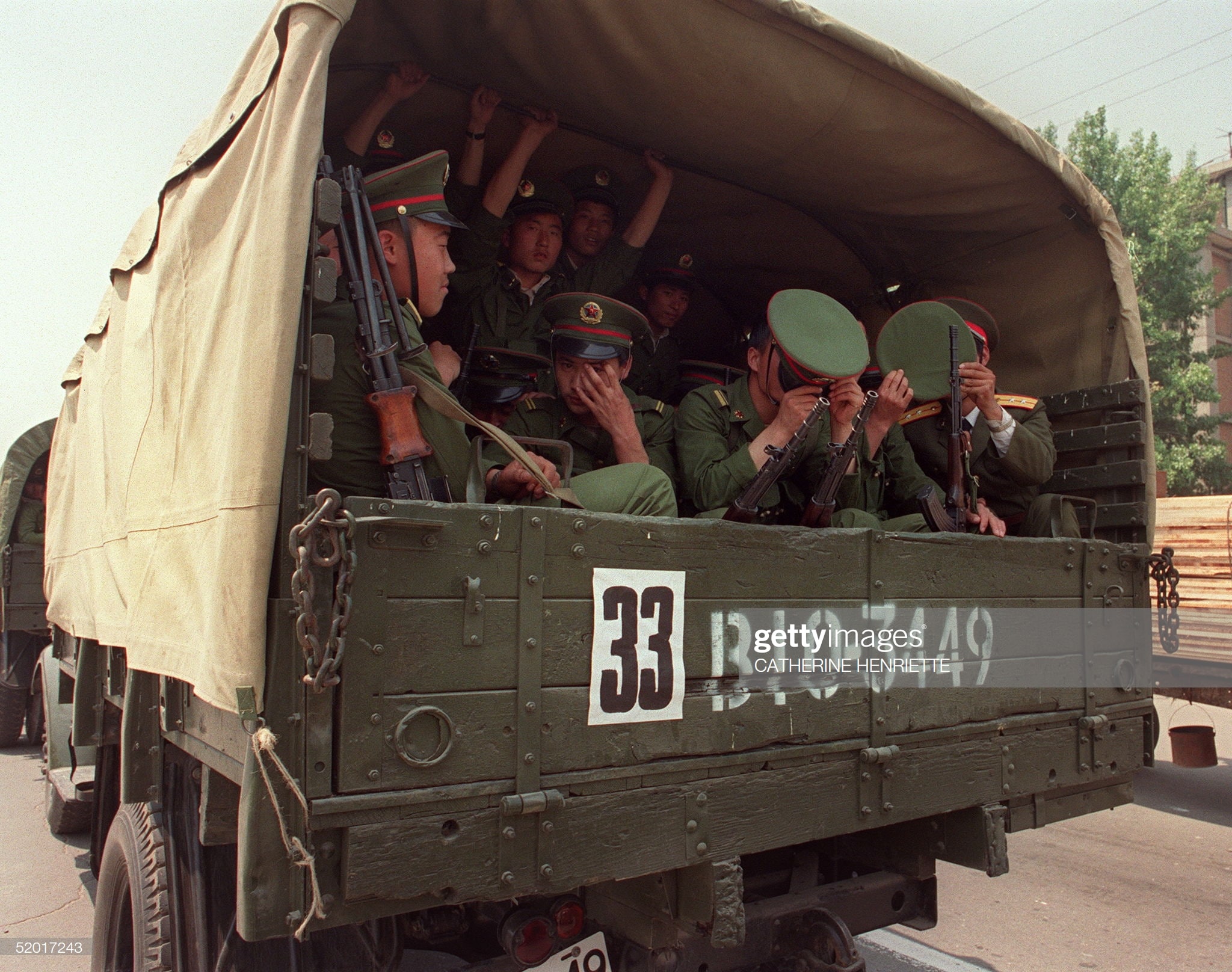 BEIJING CHINA - MAY 20 Armed soldiers of Peoples Liberation Army PLO hide their faces when they are photographed 20 May 1989 in Beijing on their way to Tiananmen Square 20 May 1989 after the Martial Law was proclaimed in Beijing 20 May In a show of force 04 June China leaders vented their fury and frustration n student dissidents and their pro-democracy supporters Several hundred people have been killed and thousands wounded when soldiers moved on Tiananmen Square during a violent military crackdown ending six weeks of student demonstrations Photo credit should read CATHERINE HENRIETTEAFPGetty Images